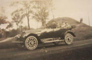 John E driving (possibly 1916 Studebaker SF)
